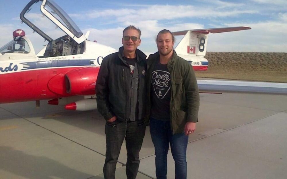 Two men standing in front of a plane Description automatically generated with medium confidence