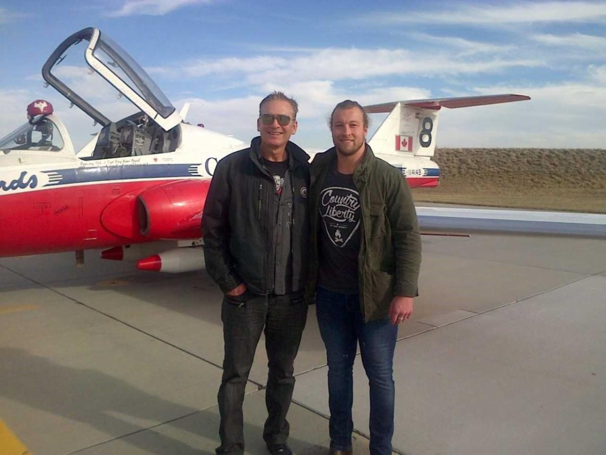 Two men standing in front of a plane Description automatically generated with medium confidence