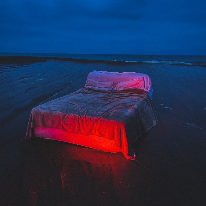 A bed on a beach at night Description automatically generated