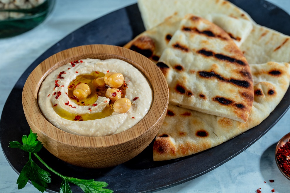A bowl of hummus and pita bread on a plate

Description automatically generated