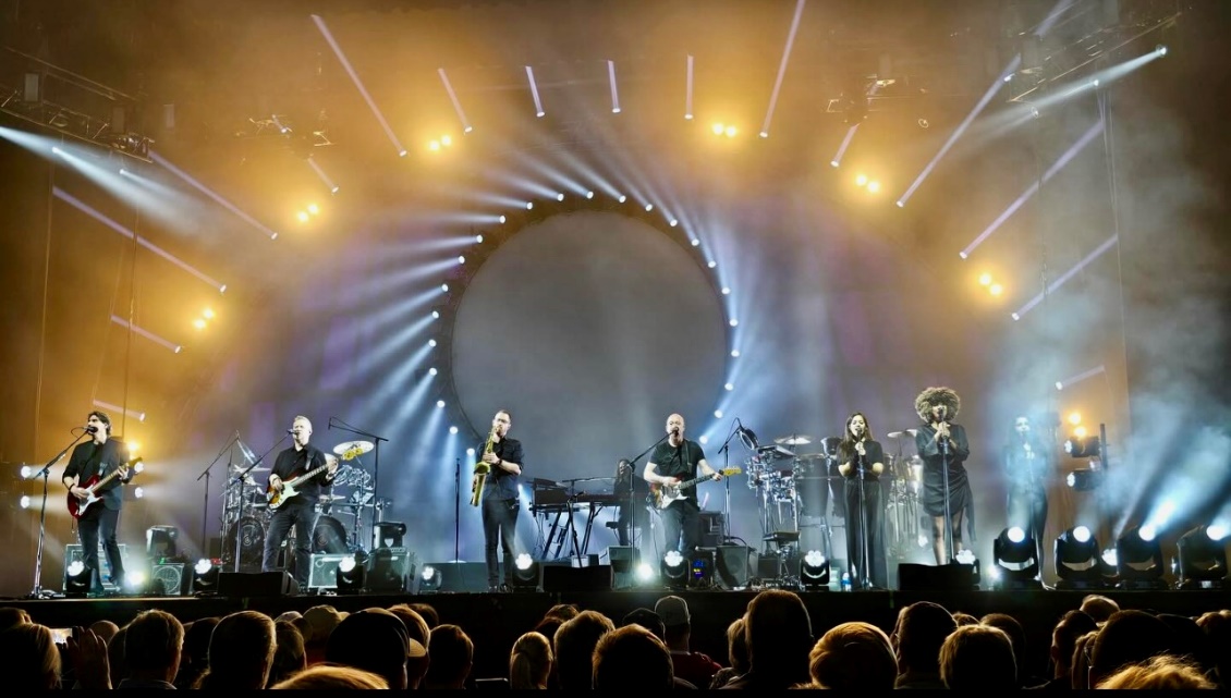 A group of people on stage with lights and a circle Description automatically generated