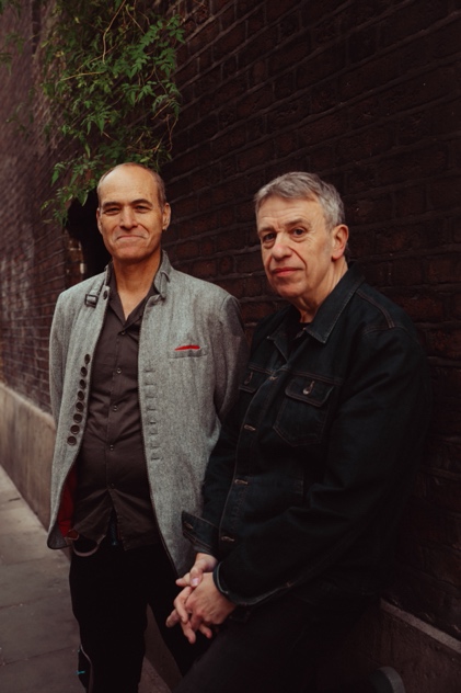Medium shot of men standing next to a brick wall

Description automatically generated
